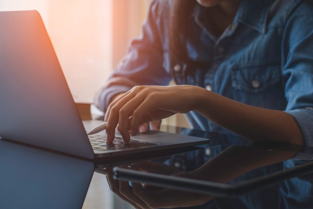 Woman (without face in frame) browsing on her laptop.